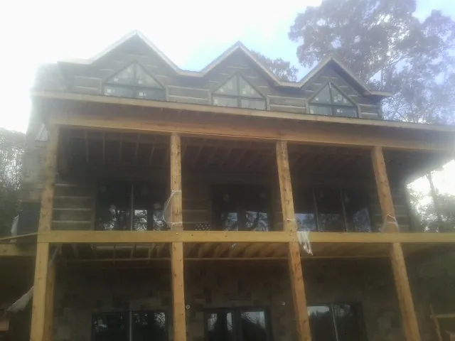 Dormers and porch framing on a large log home under construction — Roof Coating work by our crew in Le Mars