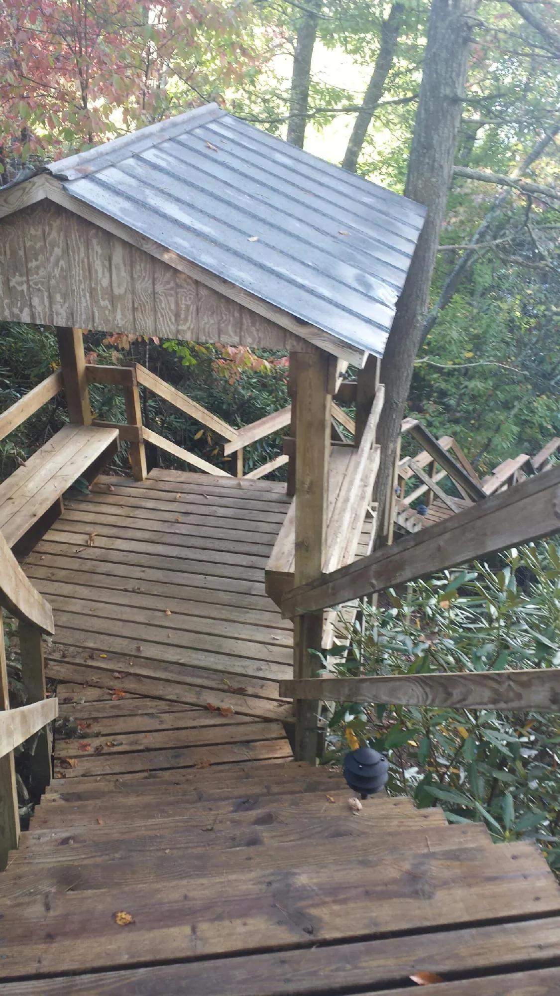 Metal roofed shelter over wooden steps on a wooded walkway — Skylight Repair & Installation work by our crew in Le Mars