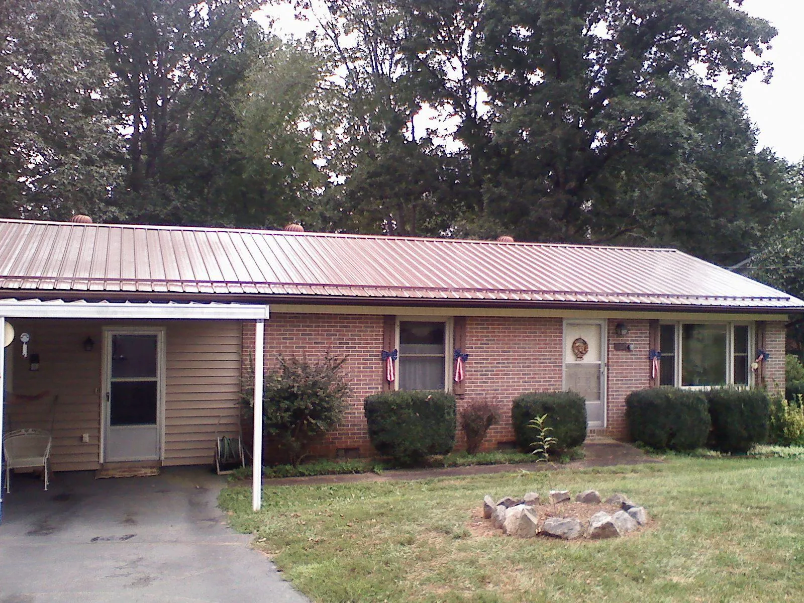 Bronze metal roof and carport on a brick ranch home — Roof Repair work by our crew in Le Mars