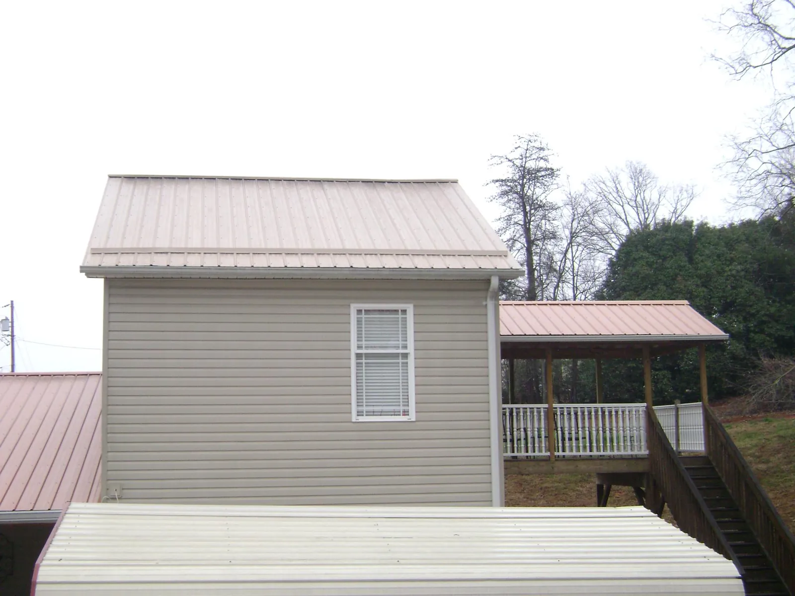 Tan metal roofs on a two story addition and attached porch, from a Roof Replacement job in Le Mars