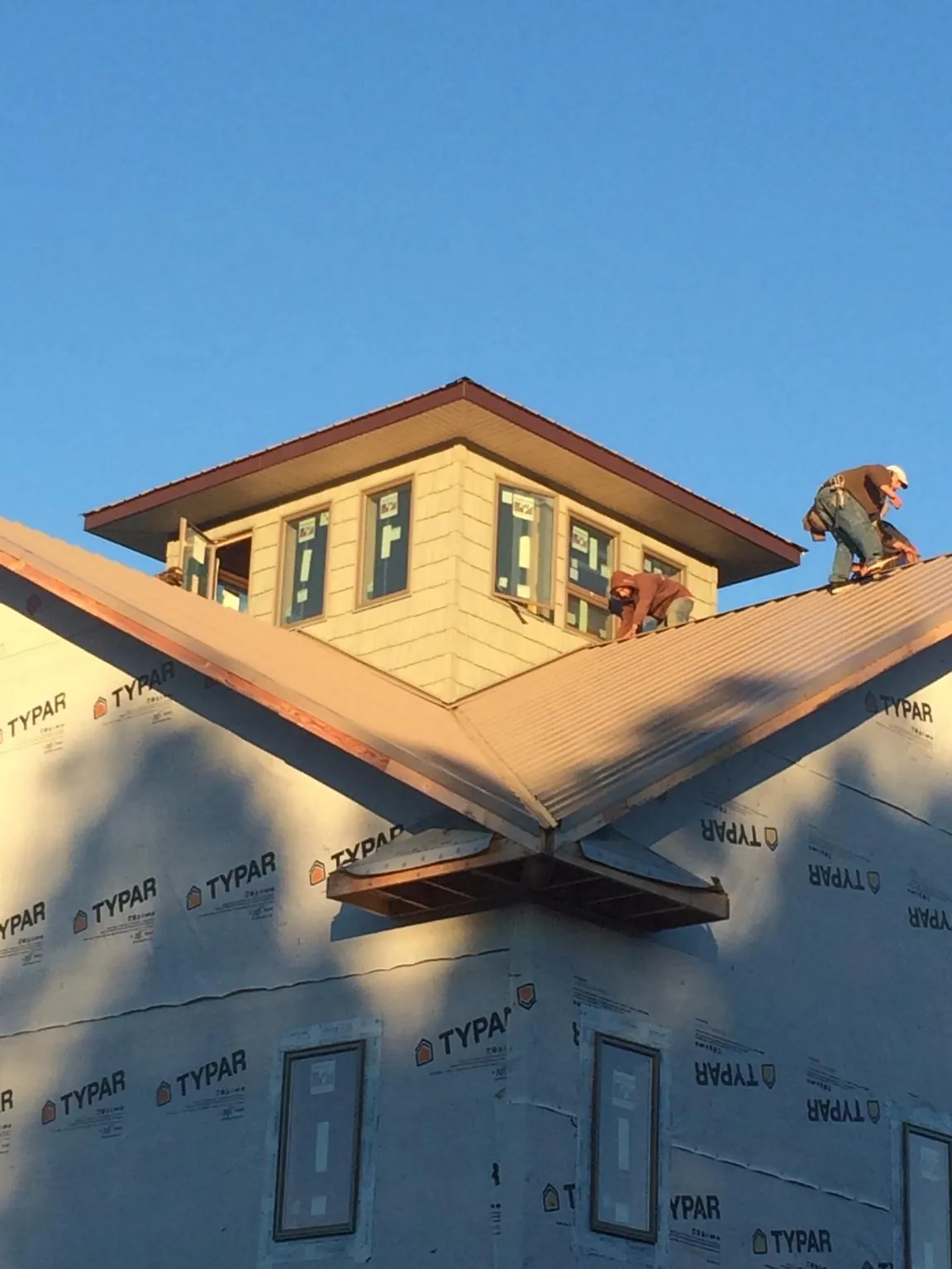 Roofers working around a rooftop cupola on a new metal roof at sunset — Roof Waterproofing in Le Mars by Roofing Brothers
